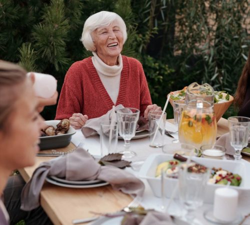 Femme senior rit durant son repas entourée de sa famille