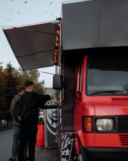 Food truck rouge sert à manger à deux jeunes hommes
