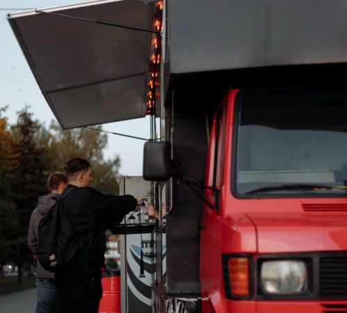 Food truck rouge sert à manger à deux jeunes hommes